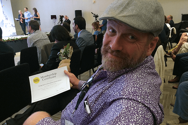 Photo d'André Gobeil tenant en main le certificat de membre ENoLL du LLio
